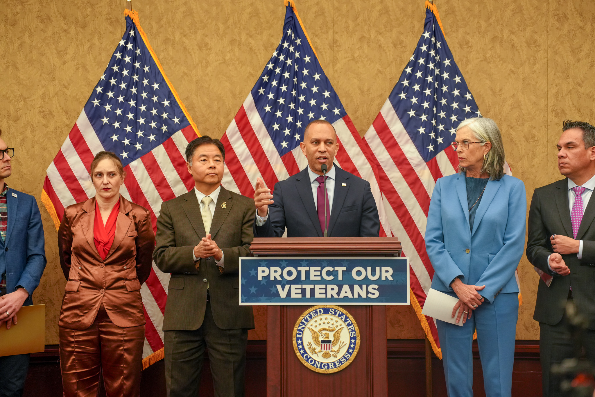 Leader Jeffries speaking with a podium sign reading "Protect Our Veterans"