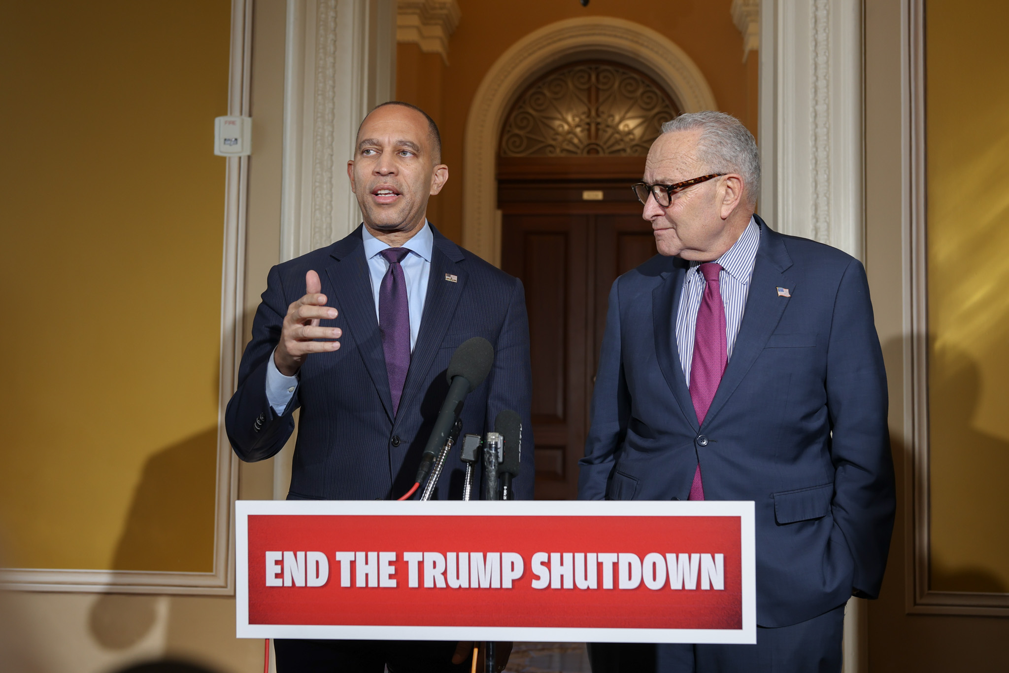 Leader Jeffries (left) and Leader Schumer (right) speaking with a sign reading "End the Trump Shutdown"