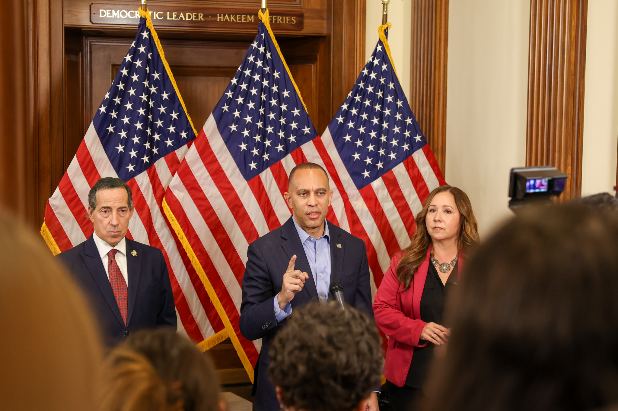 Rep. Jamie Raskin (left), Leader Jeffries (center), Rep.-Elect Adelita Grijalva (right) speaking at press conference in front of three American flags