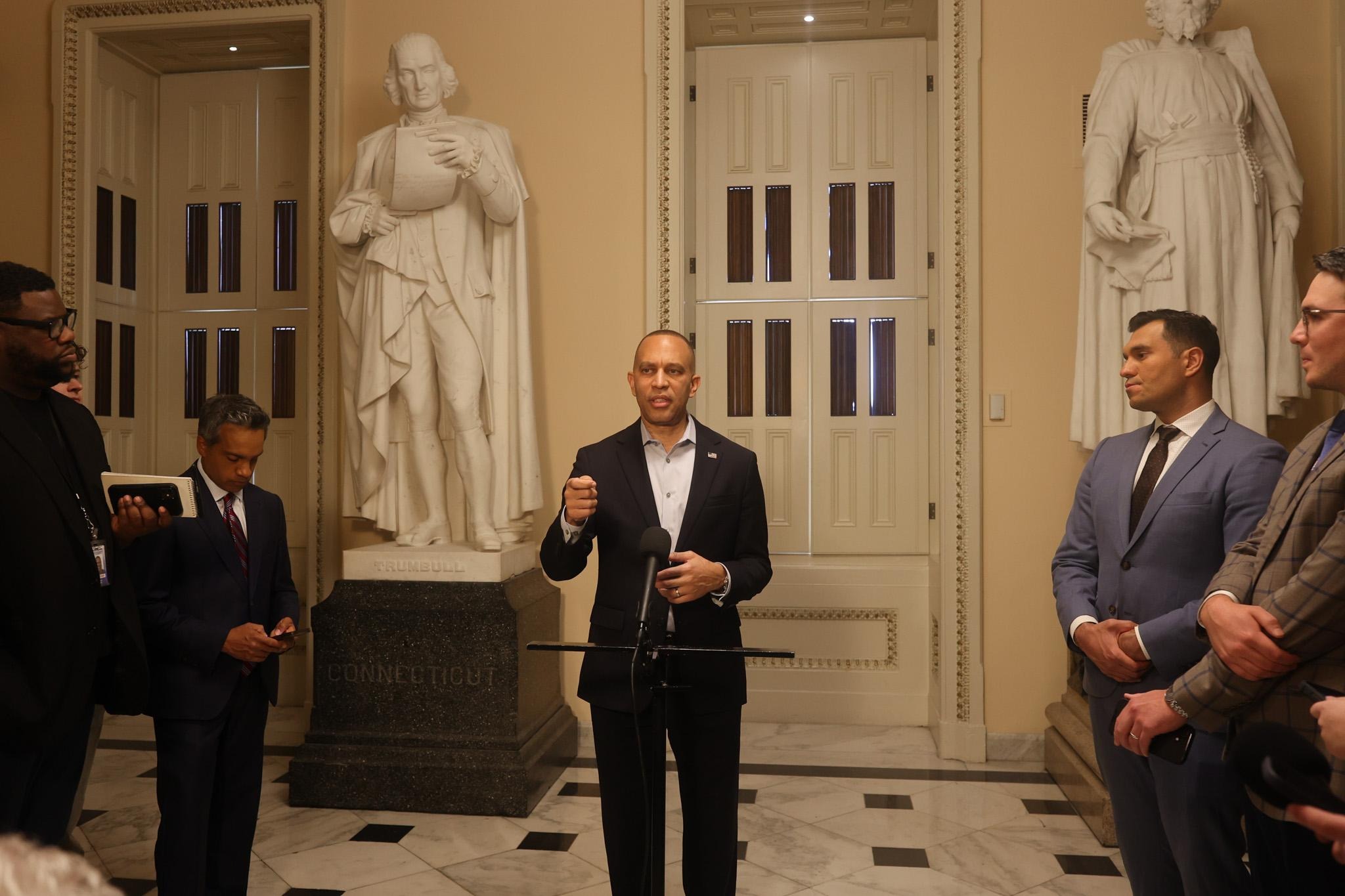 Leader Jeffries speaking at a press conference in front of statues