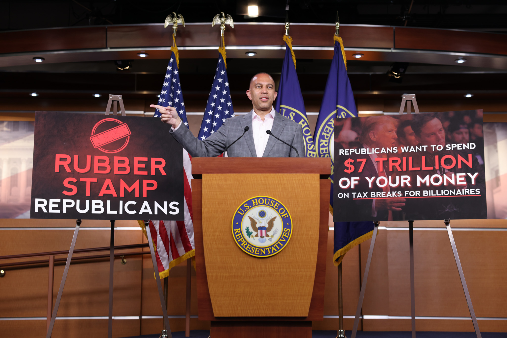 Leader Jeffries Speaking at Weekly Press Conference between posters reading "Rubber Stamp Republicans" and "Republicans Want to Spend $7 Trillion of Your Money on Tax Breaks for Billionaires"