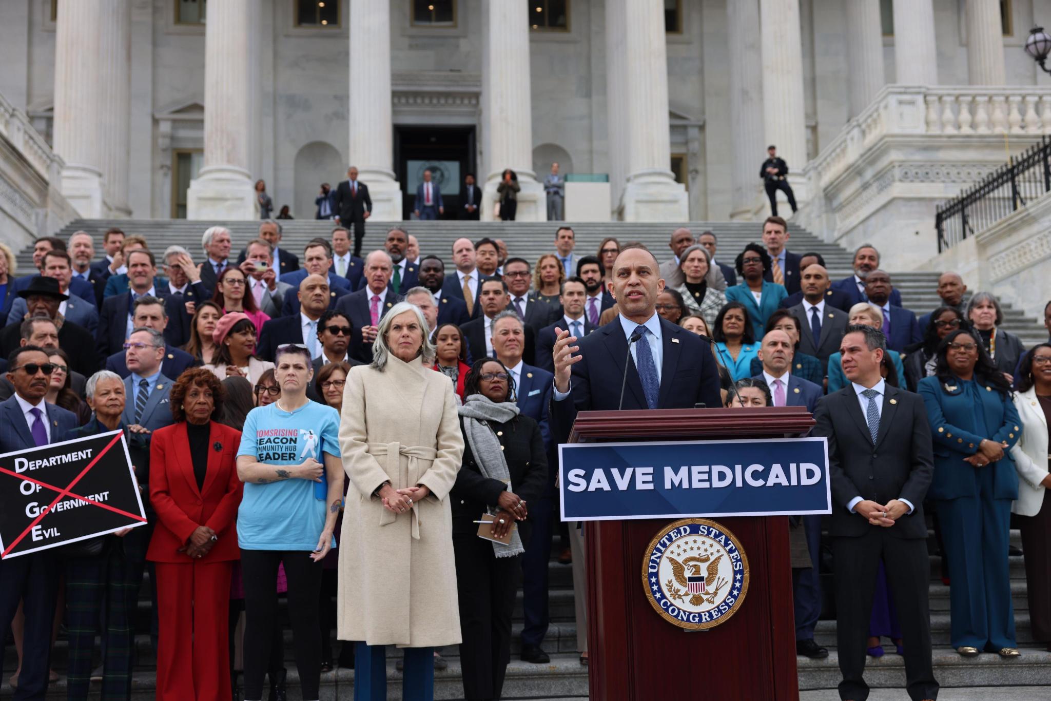 Leader Jeffries speaking from podium, joined by members of the House Democratic Caucus and Leslie Bernedo, Mary Beth Cochran and Katina Moss 