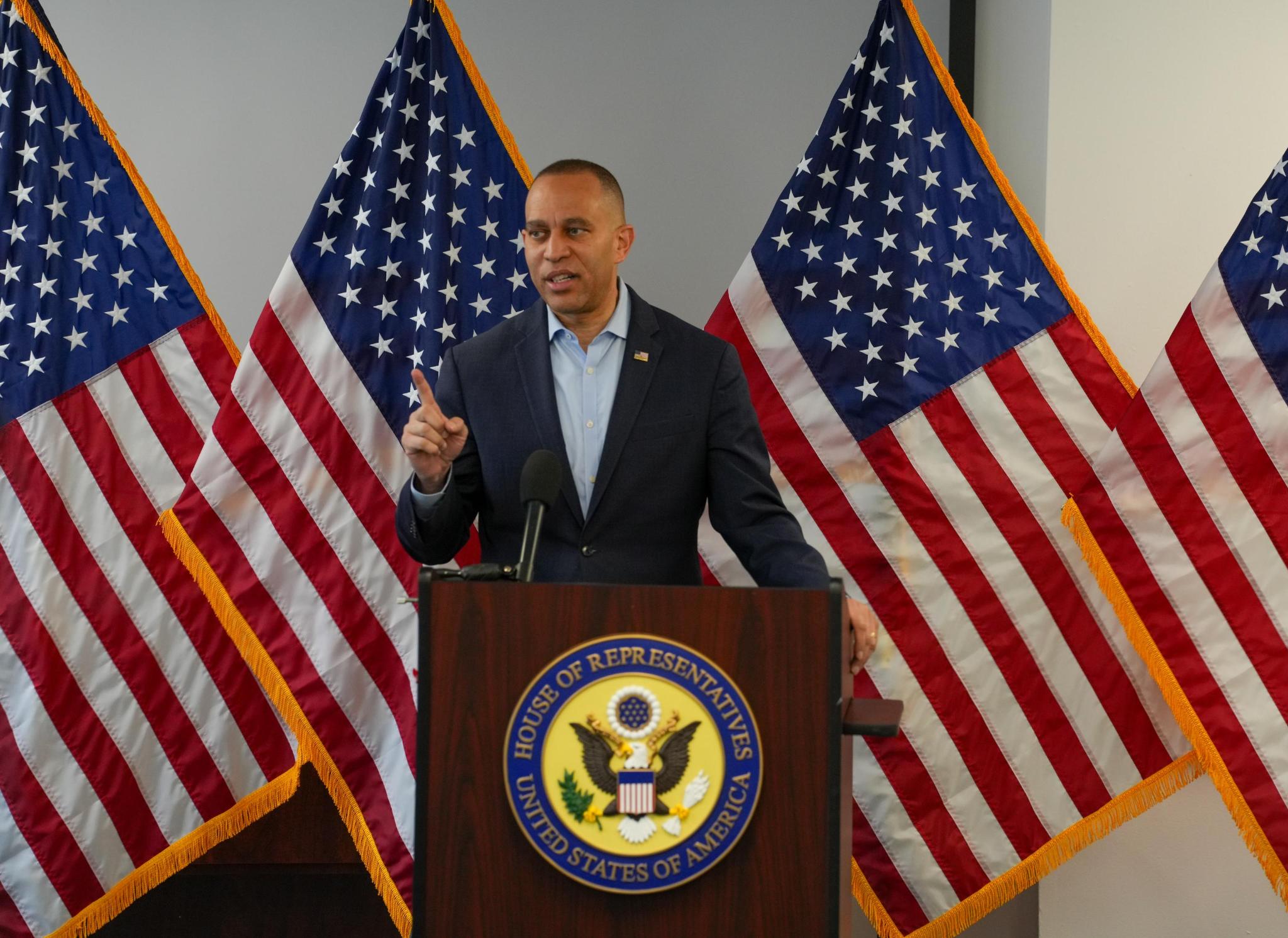 Leader Jeffries speaking at press conference in front of four American flags