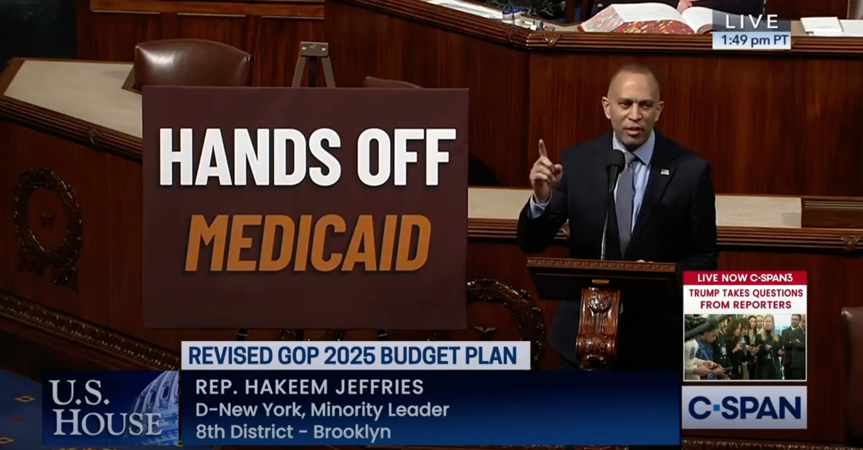 Leader Jeffries speaking on the House Floor with a poster on the right reading "Hands Off Medicaid"