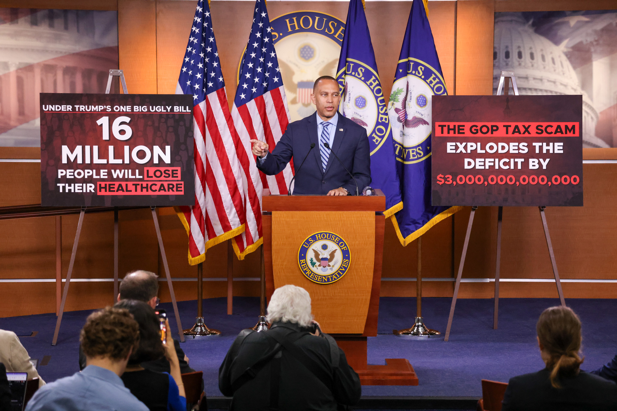 Leader Jeffries Speaking at Weekly Press Conference in between signs reading "Under Trump's One Big Ugly Bill 16 Million People Will Lose Their Healthcare" and "The GOP Tax Scam Explodes The Deficit By $3,000,000,000,000"