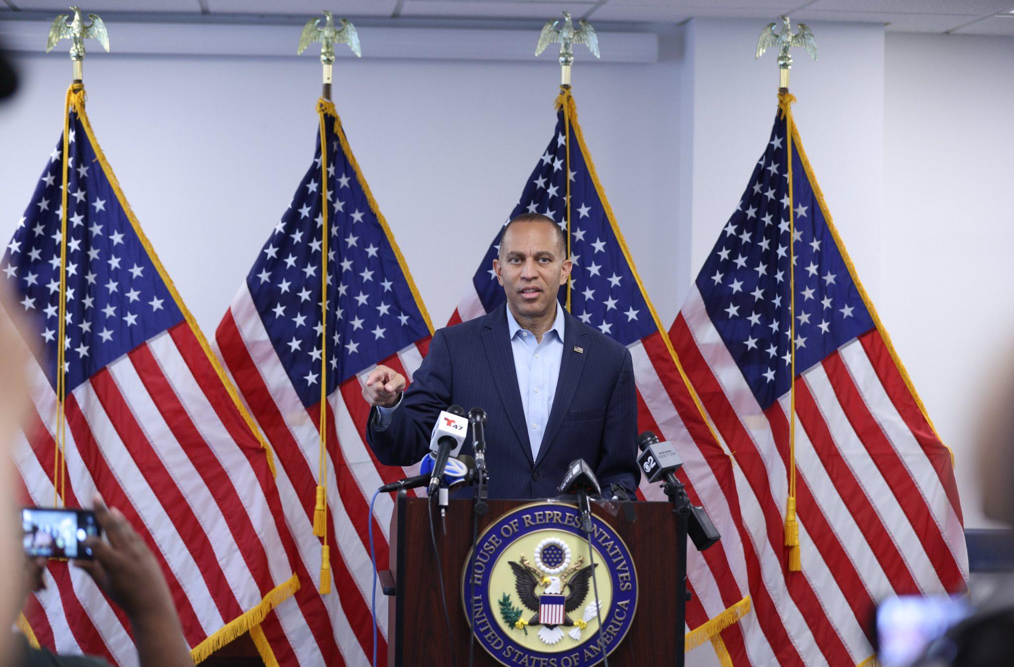 Leader Jeffries speaking at press conference in front of four American flags
