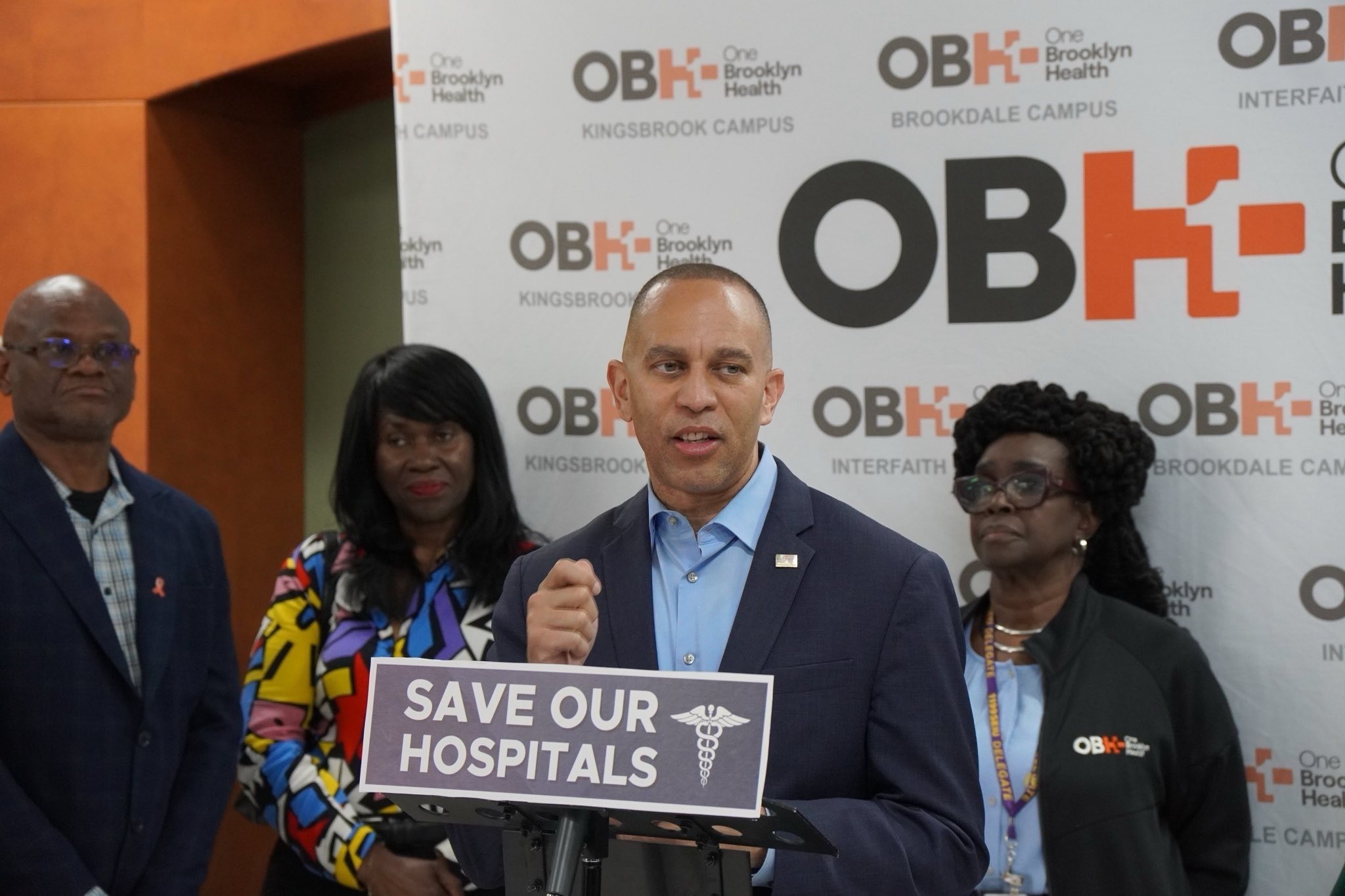 Leader Jeffries speaking behind a podium with a sign that reads "Save Our Hospitals"