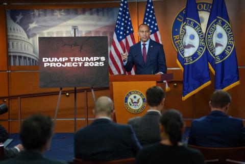 Leader Jeffries speaking at Weekly Press Conference with a poster that reads '#DumpTrump'sProject2025' 