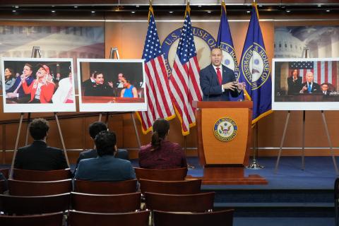 Leader Jeffries Speaking at Weekly Press Conference with three posters (from left, Marjorie Taylor Greene wearing a Make America Great Again hat, George Santos and Lauren Boebert speaking on the House Floor, President Biden delivering his State of the Union address with Vice President Harris standing and applauding in background while Speaker Johnson remains seated