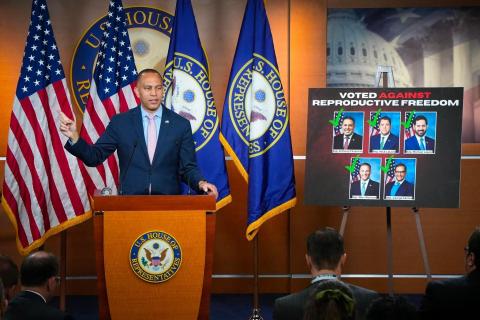 Leader Jeffries pointing next to a poster of New York House Republicans who voted against reproductive freedom